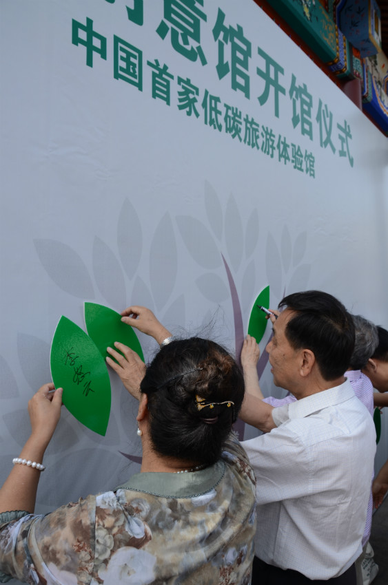 参会嘉宾为零碳创意馆“环保树”添上绿色标签，并做了“低碳环保”主题的题词